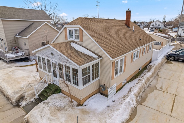 back of property with a chimney, a shingled roof, a sunroom, fence, and driveway