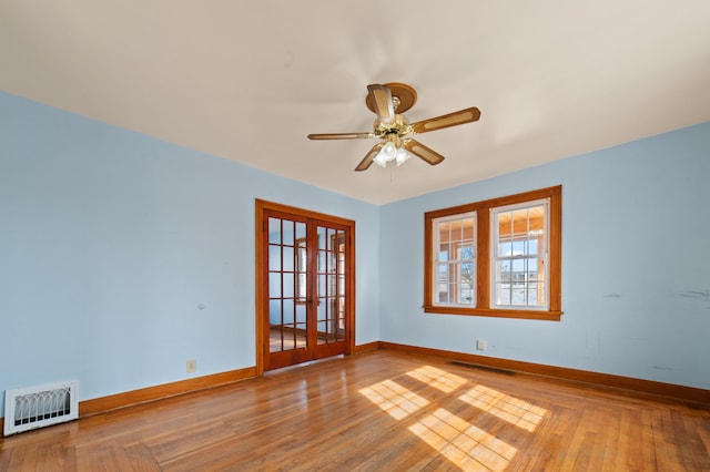 spare room with baseboards, visible vents, a ceiling fan, hardwood / wood-style floors, and french doors