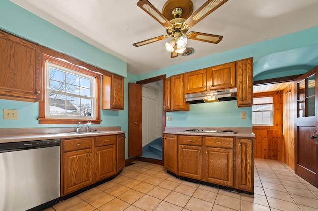 kitchen featuring brown cabinets, stainless steel appliances, light countertops, under cabinet range hood, and a sink