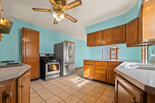 kitchen featuring a sink, a ceiling fan, light countertops, appliances with stainless steel finishes, and brown cabinetry