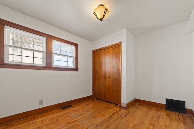 unfurnished bedroom with light wood-style floors, a closet, visible vents, and baseboards