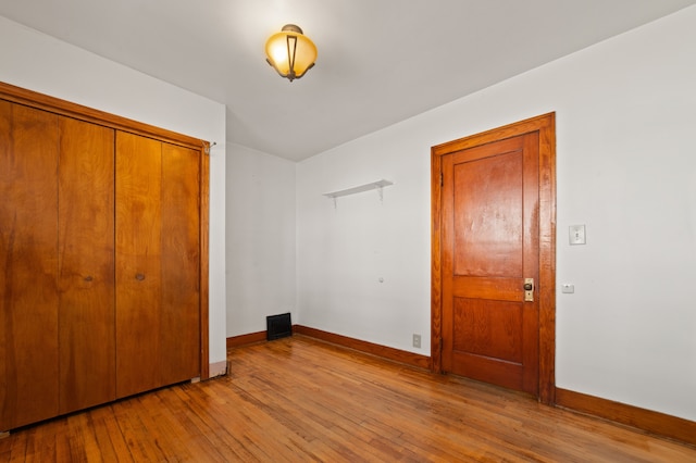 unfurnished bedroom with a closet, baseboards, and light wood finished floors