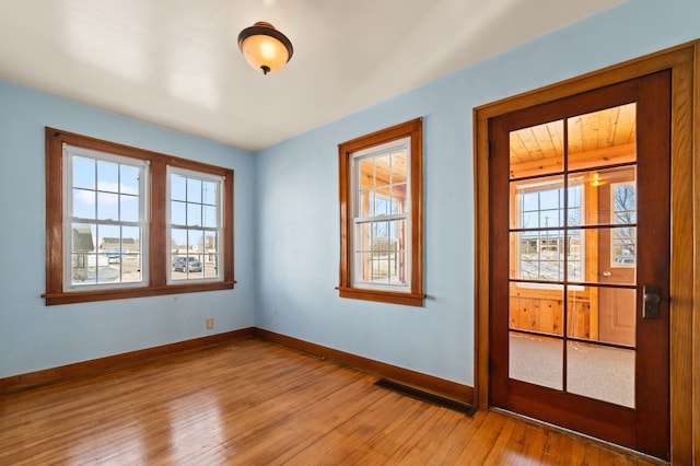 doorway featuring a healthy amount of sunlight, baseboards, visible vents, and light wood-style flooring