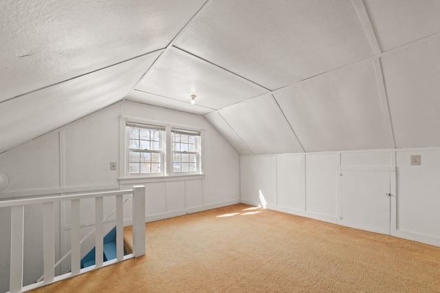 bonus room featuring carpet, vaulted ceiling, and a decorative wall