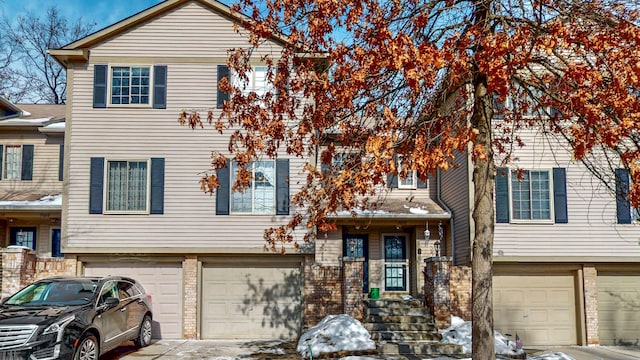 multi unit property featuring an attached garage, driveway, and brick siding