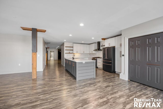 kitchen featuring white cabinets, premium appliances, wall chimney exhaust hood, light countertops, and a sink