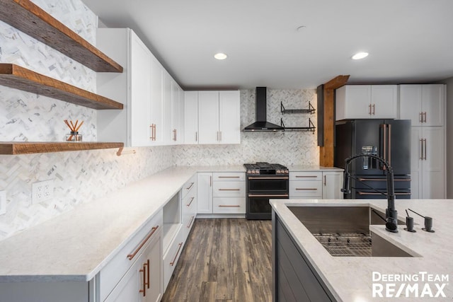 kitchen featuring open shelves, range with two ovens, black fridge, and wall chimney range hood