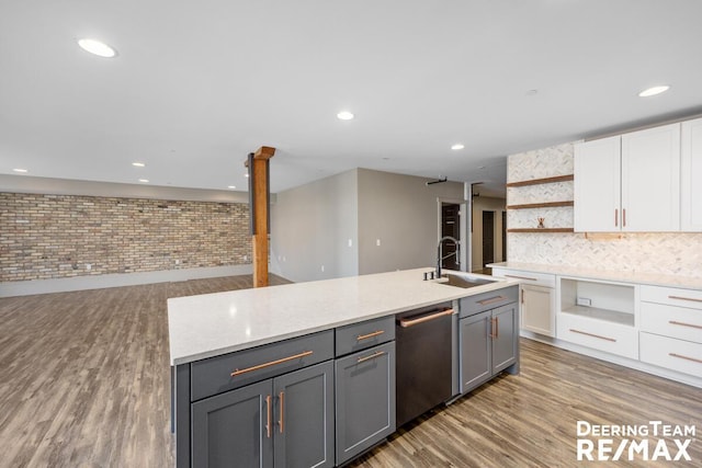 kitchen featuring wood finished floors, a sink, white cabinetry, dishwasher, and open shelves