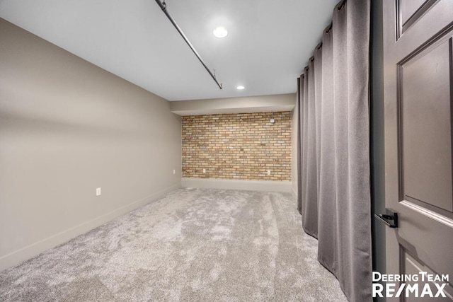 carpeted spare room featuring recessed lighting, baseboards, and brick wall