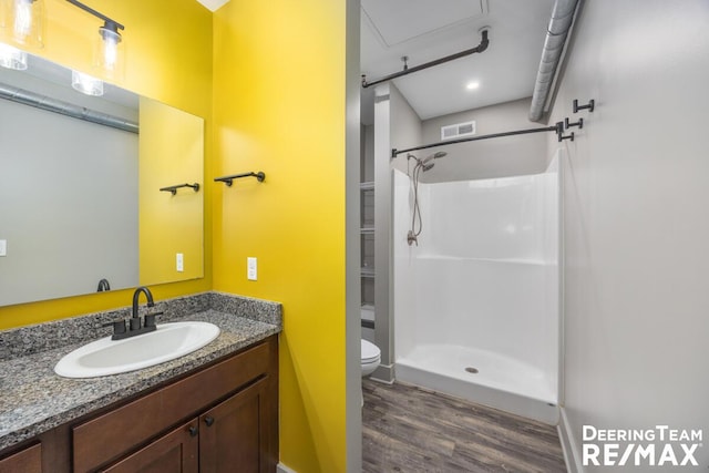 full bath with visible vents, toilet, a stall shower, vanity, and wood finished floors