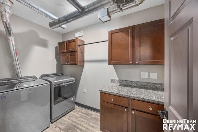 washroom with light wood-style flooring, washer and clothes dryer, cabinet space, and baseboards