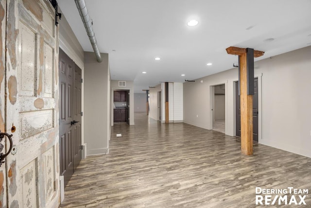 interior space with a barn door, wood finished floors, visible vents, and recessed lighting