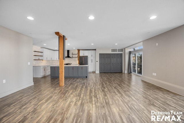 unfurnished living room featuring baseboards, wood finished floors, visible vents, and recessed lighting