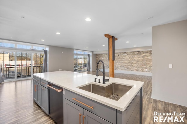 kitchen with gray cabinets, open floor plan, a sink, wood finished floors, and dishwasher