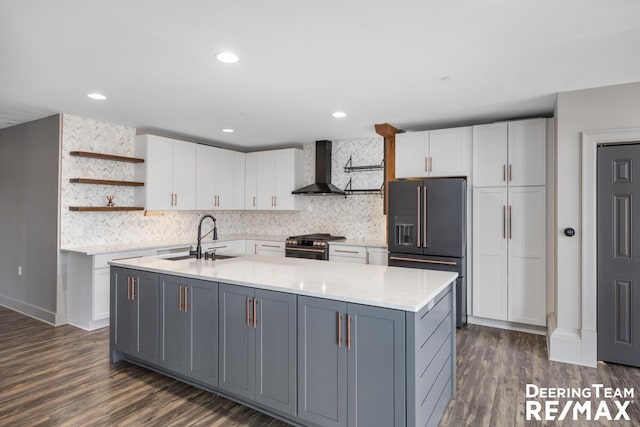 kitchen featuring open shelves, white cabinets, a sink, high quality appliances, and wall chimney exhaust hood