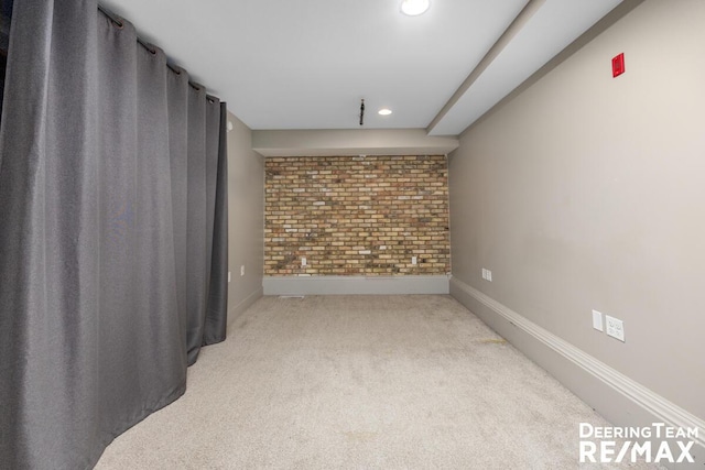 carpeted empty room with brick wall, recessed lighting, and baseboards