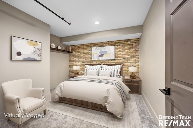 carpeted bedroom with brick wall and baseboards