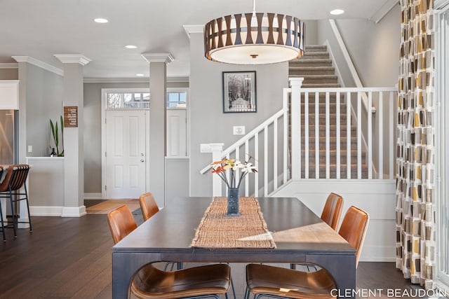 dining area featuring dark wood-style floors, ornate columns, ornamental molding, baseboards, and stairs