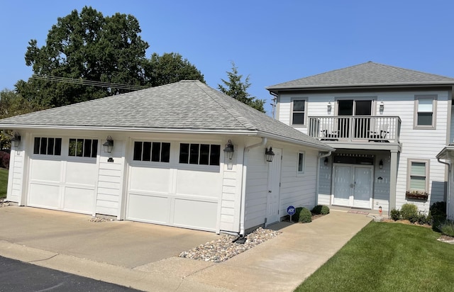 exterior space featuring a balcony, a shingled roof, a front lawn, and an outdoor structure