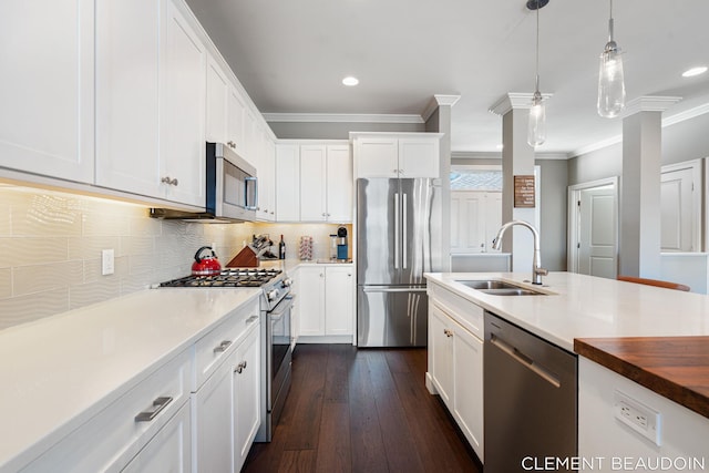 kitchen with a sink, white cabinets, appliances with stainless steel finishes, tasteful backsplash, and crown molding