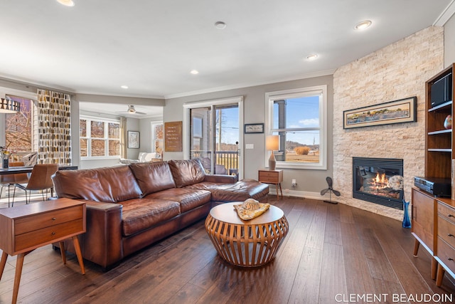 living room featuring baseboards, dark wood finished floors, crown molding, a fireplace, and recessed lighting