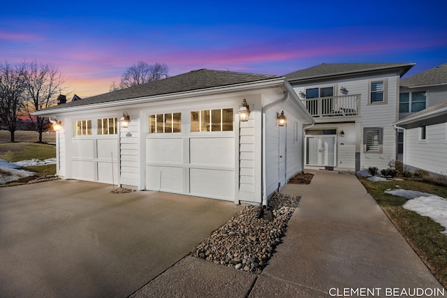 view of front of house featuring driveway, an attached garage, a balcony, and an outdoor structure