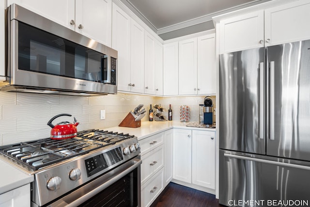 kitchen with stainless steel appliances, light countertops, backsplash, and white cabinetry