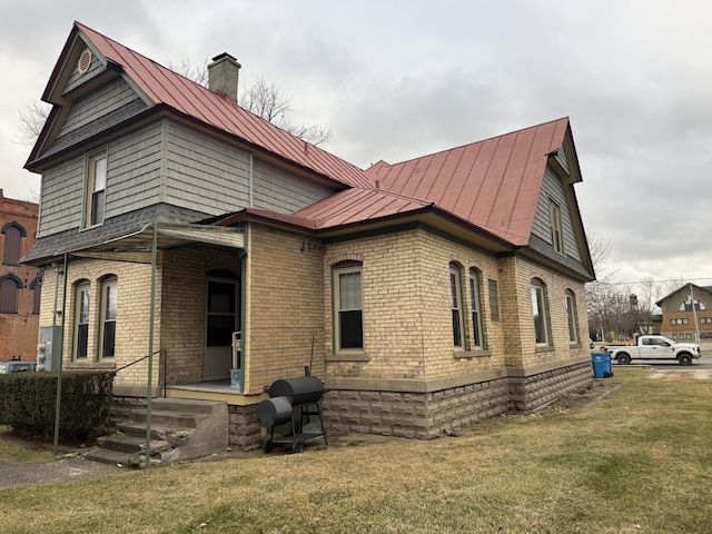 exterior space with metal roof, brick siding, a standing seam roof, and a lawn