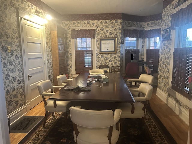 dining space with wood finished floors, visible vents, baseboards, and wallpapered walls