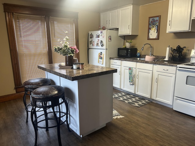 kitchen with white appliances, dark wood-style flooring, dark countertops, and a kitchen bar