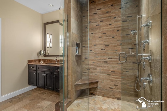 full bath featuring a stall shower, vanity, and baseboards