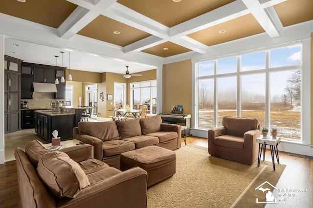 living area featuring light wood-type flooring, beamed ceiling, coffered ceiling, and visible vents