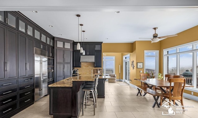 kitchen with stainless steel appliances, a breakfast bar, light stone countertops, tasteful backsplash, and glass insert cabinets