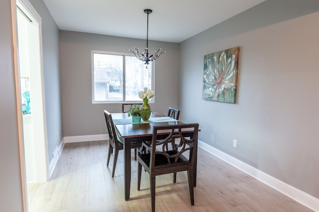 dining area featuring baseboards, a chandelier, and light wood-type flooring