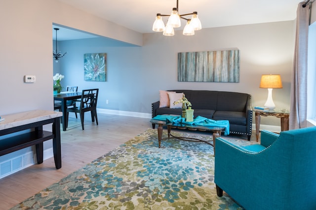 living room featuring a chandelier, visible vents, baseboards, and wood finished floors