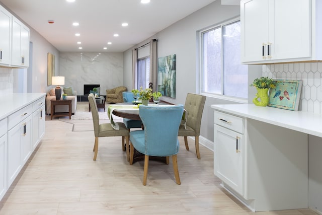 dining room with a fireplace, recessed lighting, light wood-style floors, and baseboards