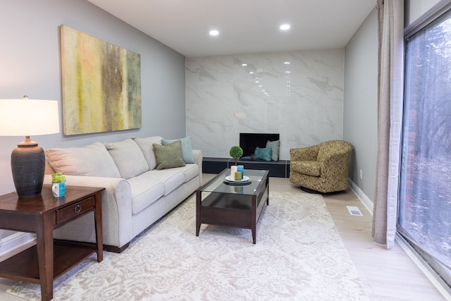 living area with visible vents, recessed lighting, an accent wall, and light wood-style floors