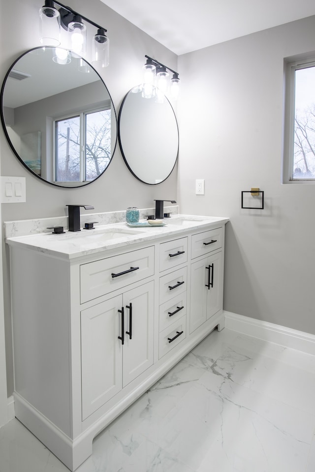 full bathroom featuring a sink, baseboards, marble finish floor, and double vanity