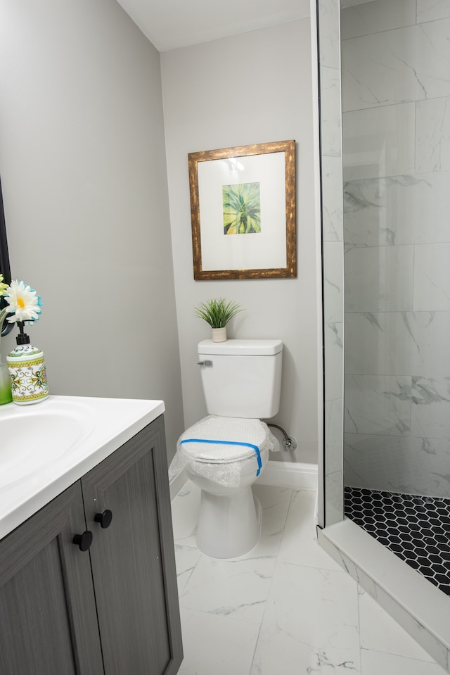 bathroom featuring baseboards, toilet, tiled shower, marble finish floor, and vanity