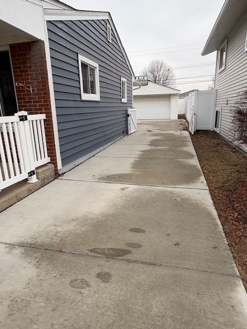 view of side of property featuring a garage, an outbuilding, brick siding, and fence