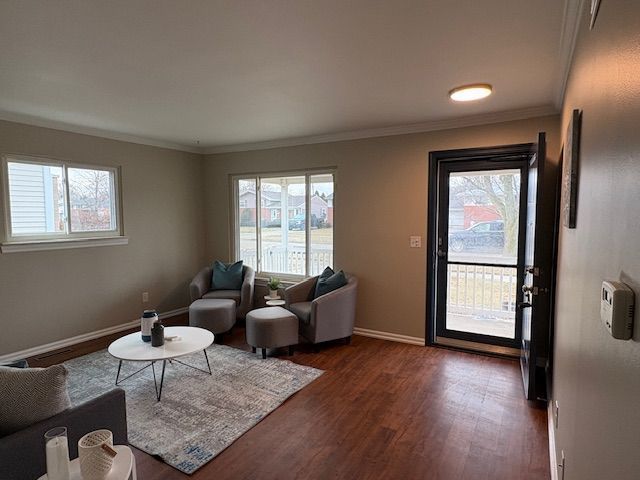 living room with crown molding, dark wood finished floors, and baseboards