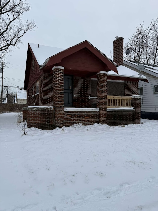 view of front of home with brick siding, a chimney, and central air condition unit