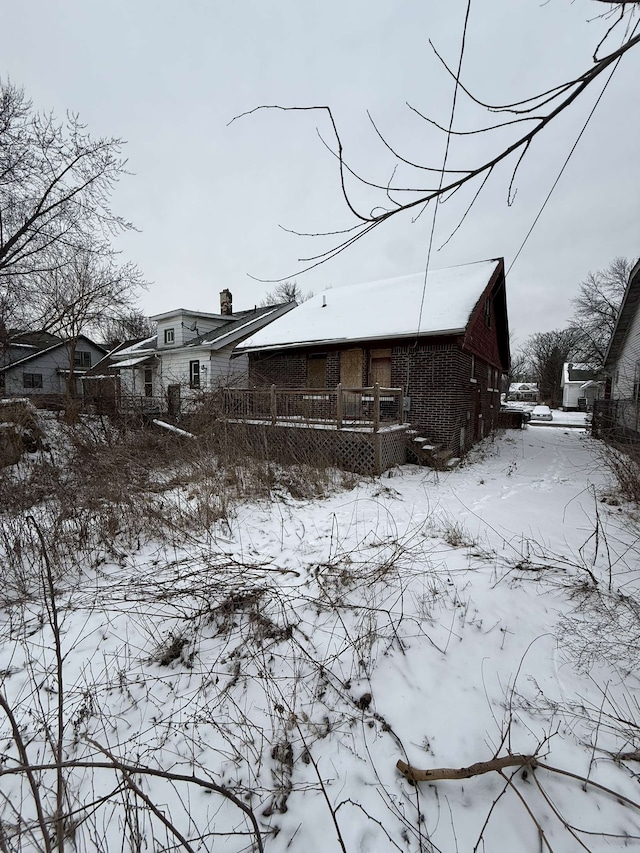 snow covered property featuring a chimney and a wooden deck