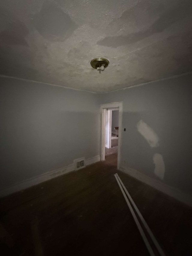 spare room featuring a textured ceiling, visible vents, and baseboards