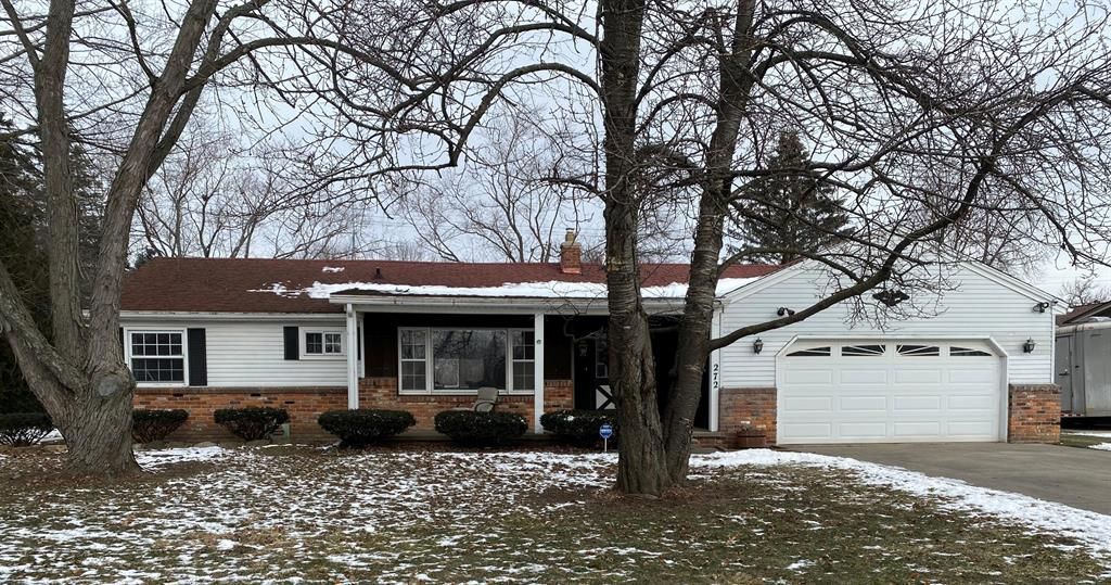 ranch-style house with brick siding, driveway, a chimney, and an attached garage