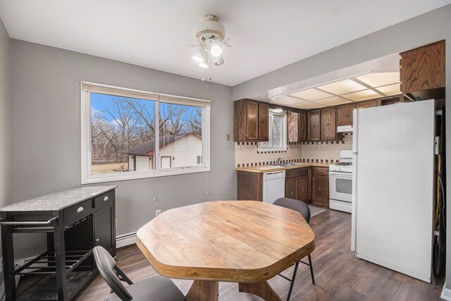 kitchen featuring white appliances, decorative backsplash, dark wood-style floors, a baseboard radiator, and light countertops