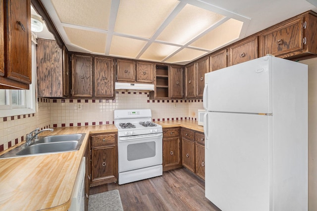 kitchen featuring under cabinet range hood, white appliances, dark wood-type flooring, a sink, and light countertops