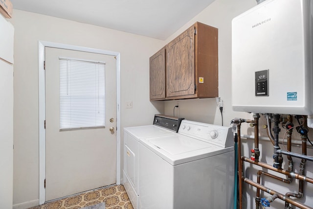 clothes washing area featuring washer and dryer, tankless water heater, and cabinet space