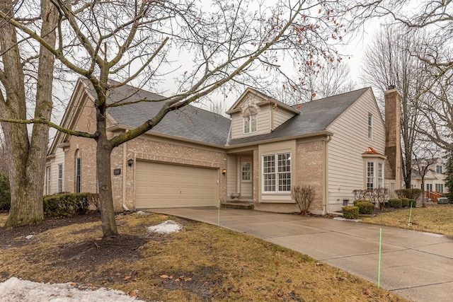 view of front facade featuring brick siding, a shingled roof, a chimney, a garage, and driveway