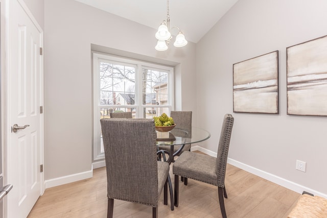 dining room with an inviting chandelier, baseboards, light wood-type flooring, and vaulted ceiling